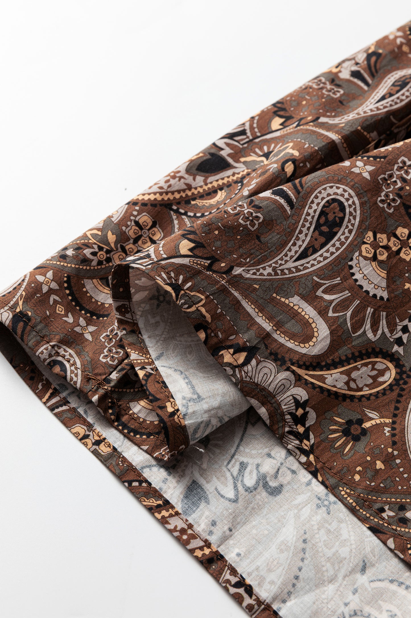 Mocha paisley babydoll mini dress with V-neckline, tie detail, long gathered sleeves, and relaxed tiered silhouette.