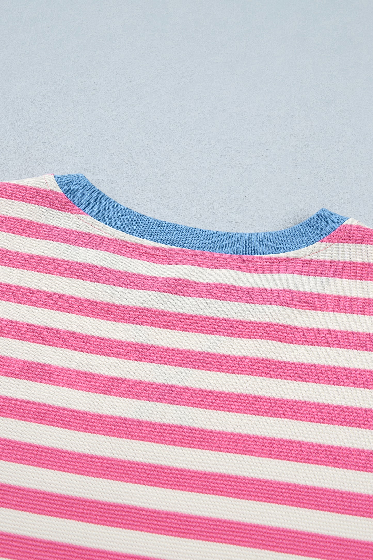 Pink and white textured striped knit short sleeve top with blue contrast ribbed neckline and sleeve cuffs, relaxed fit, and crew neckline.