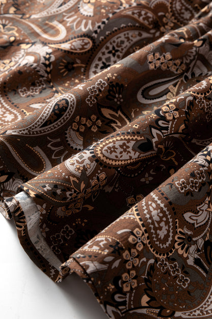 Mocha paisley babydoll mini dress with V-neckline, tie detail, long gathered sleeves, and relaxed tiered silhouette.