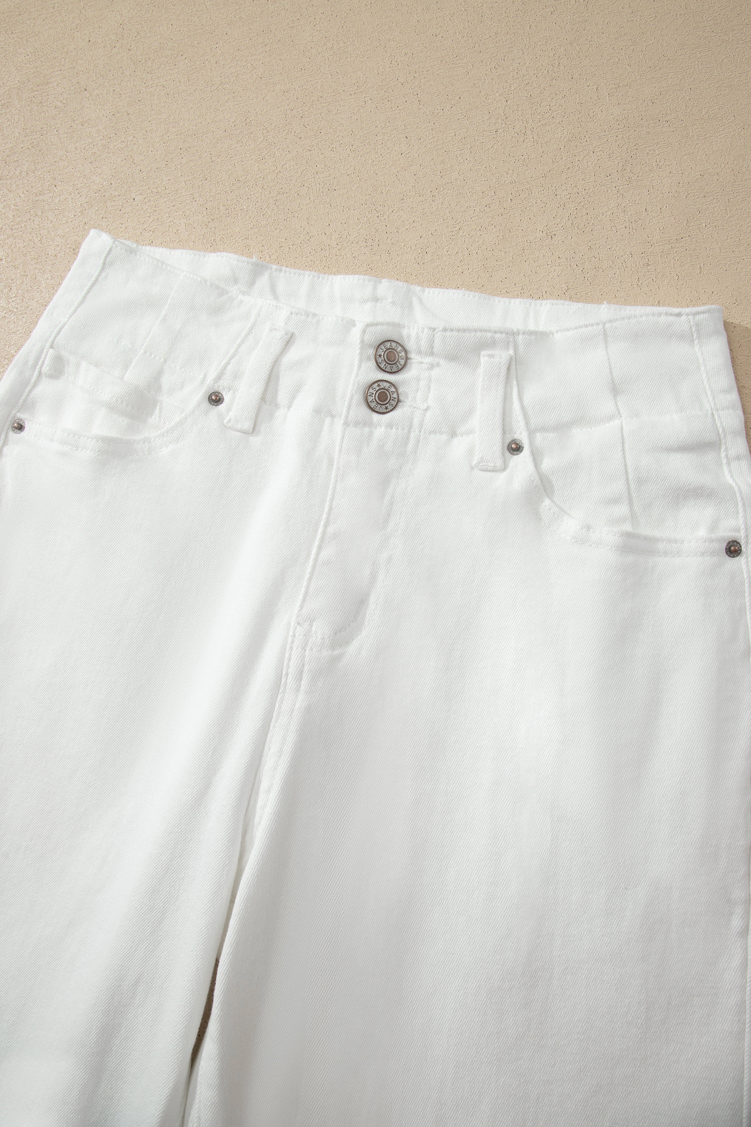White high rise wide leg jeans with double-button waistband, front pockets and cropped hem.