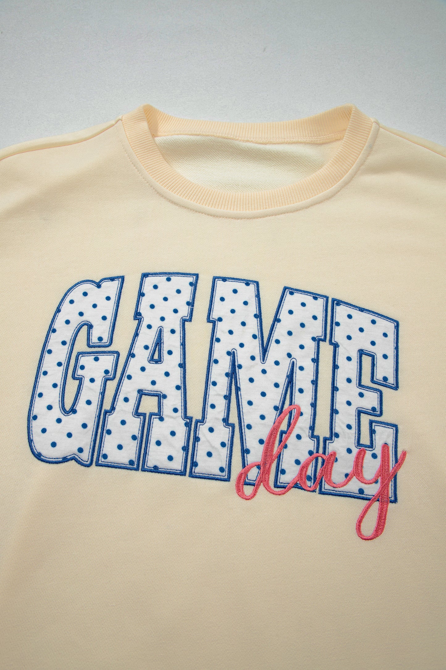 Cream Game Day embroidered sweatshirt and matching drawstring shorts set featuring long sleeves, blue contrast trim, relaxed fit, and casual sporty style.