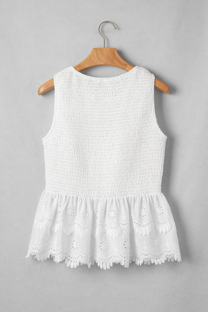 Women's white smocked sleeveless peplum top with embroidered eyelet hem, round neckline, textured bodice, and feminine boutique style.