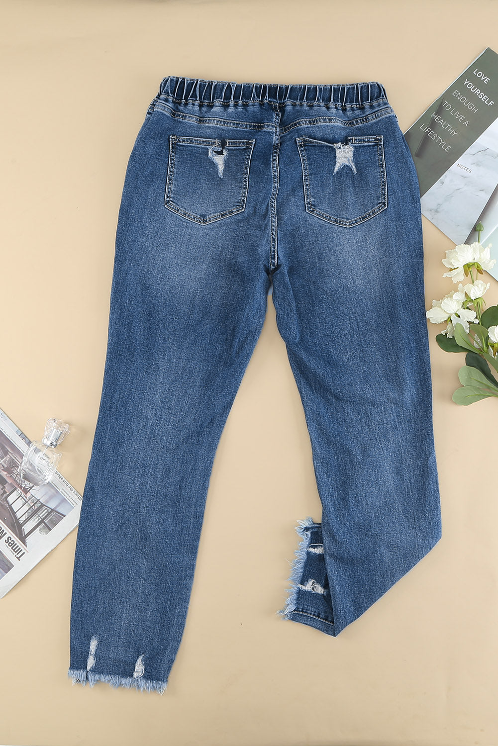 Medium wash blue distressed slim straight leg jeans with drawstring elastic waist and raw hem