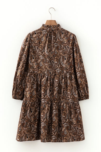 Mocha paisley babydoll mini dress with V-neckline, tie detail, long gathered sleeves, and relaxed tiered silhouette.