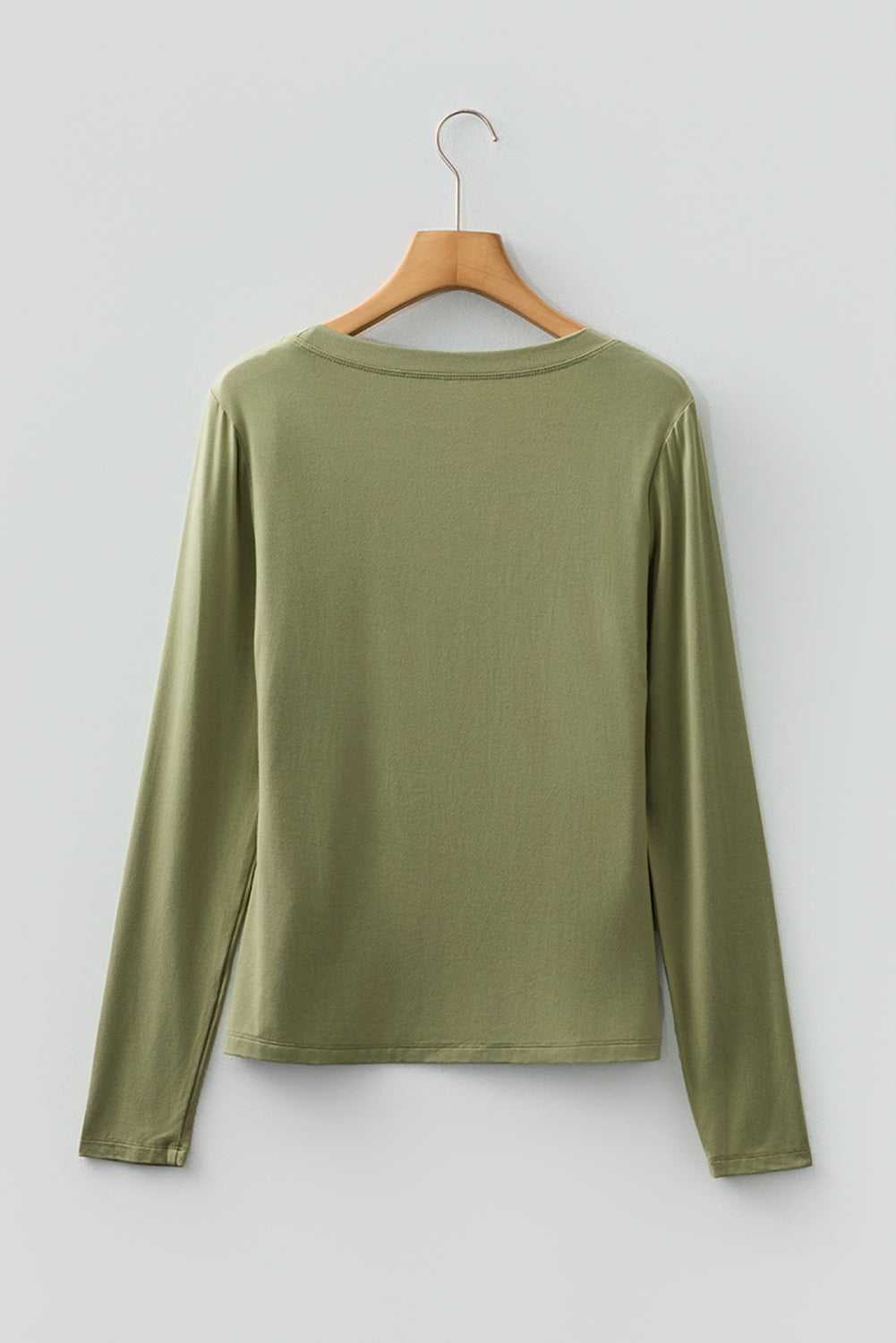 Woman wearing a Soft Sage scoop neck long sleeve top with a soft casual fit and white pants.