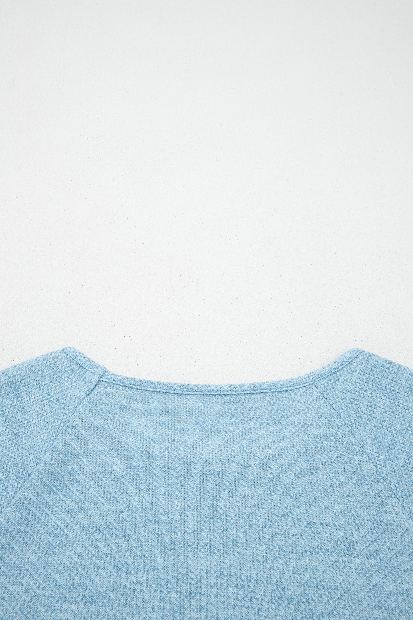 Powder Blue textured raglan long sleeve top with round neckline, relaxed fit, and curved hem