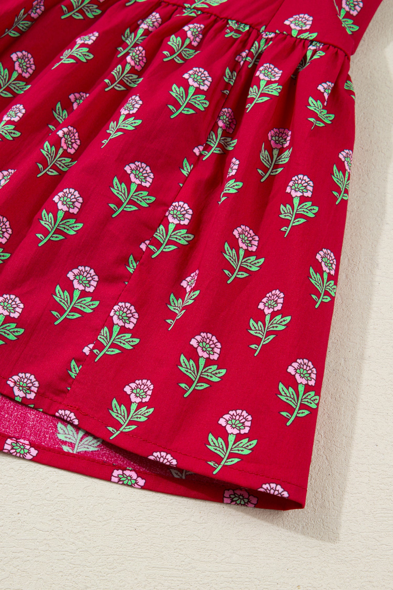 Red floral mini dress with pink collared neckline, mint scalloped trim, short puff sleeves, and a ruffled drop-waist hem