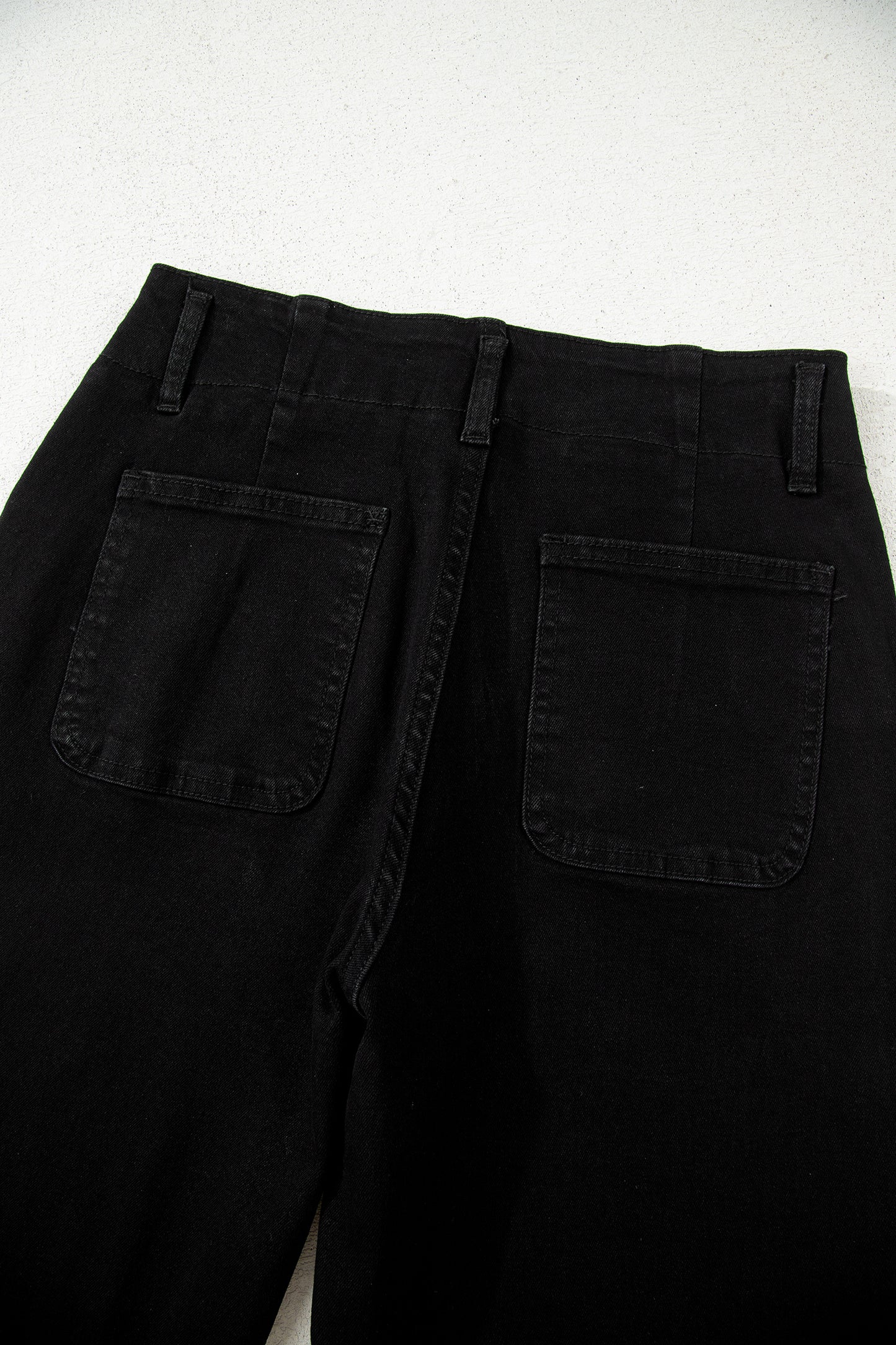 Black high rise wide leg jeans with double-button waistband, front pockets and cropped hem.