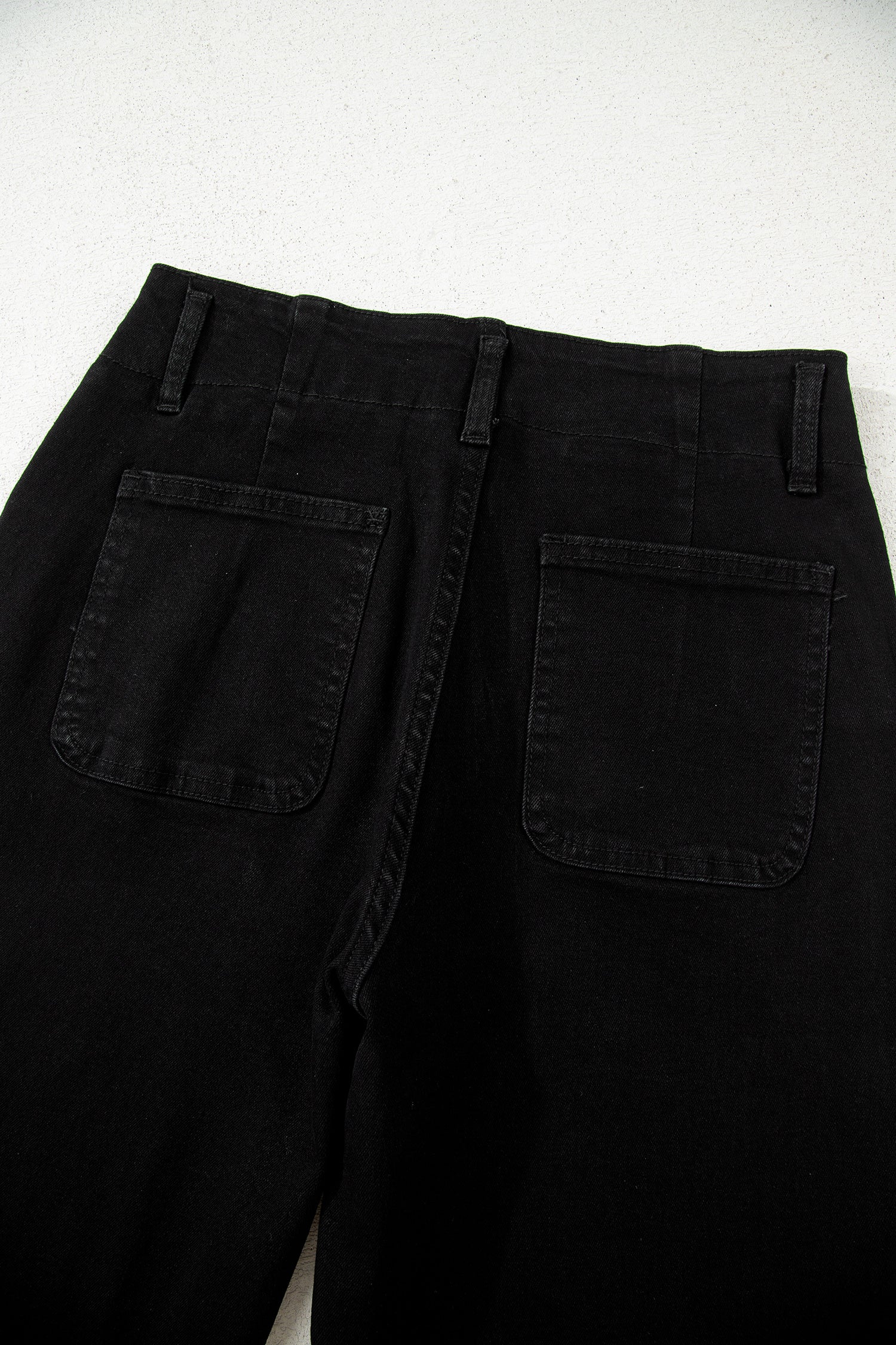 Black high rise wide leg jeans with double-button waistband, front pockets and cropped hem.