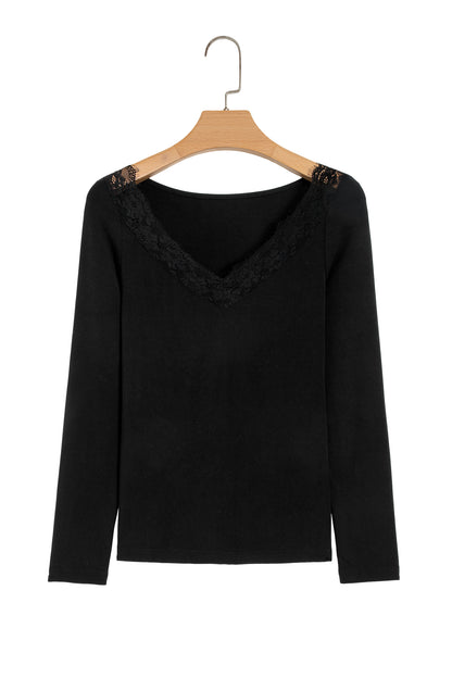 Black fitted long sleeve top with floral lace-trim V-neckline and soft stretch fabric styled with white pants.