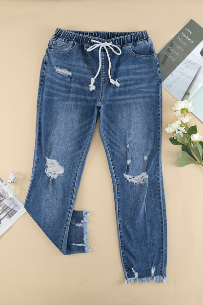 Medium wash blue distressed slim straight leg jeans with drawstring elastic waist and raw hem