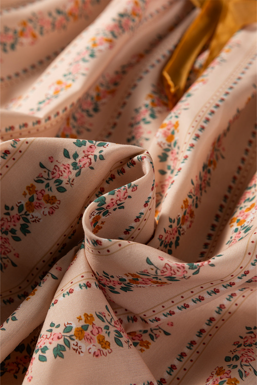Blush floral babydoll mini dress with floral stripe print, cream lace-trimmed square neckline, brown velvet bow, and long sleeves.
