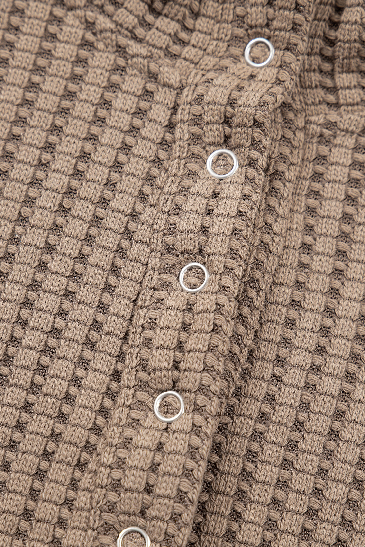 Woman wearing a Mocha textured waffle knit pullover with snap collar, relaxed long sleeves, and ribbed cuffs with white pants.
