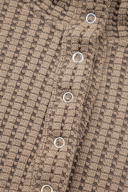 Woman wearing a Mocha textured waffle knit pullover with snap collar, relaxed long sleeves, and ribbed cuffs with white pants.