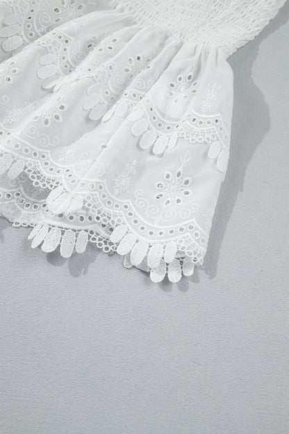 Women's white smocked sleeveless peplum top with embroidered eyelet hem, round neckline, textured bodice, and feminine boutique style.