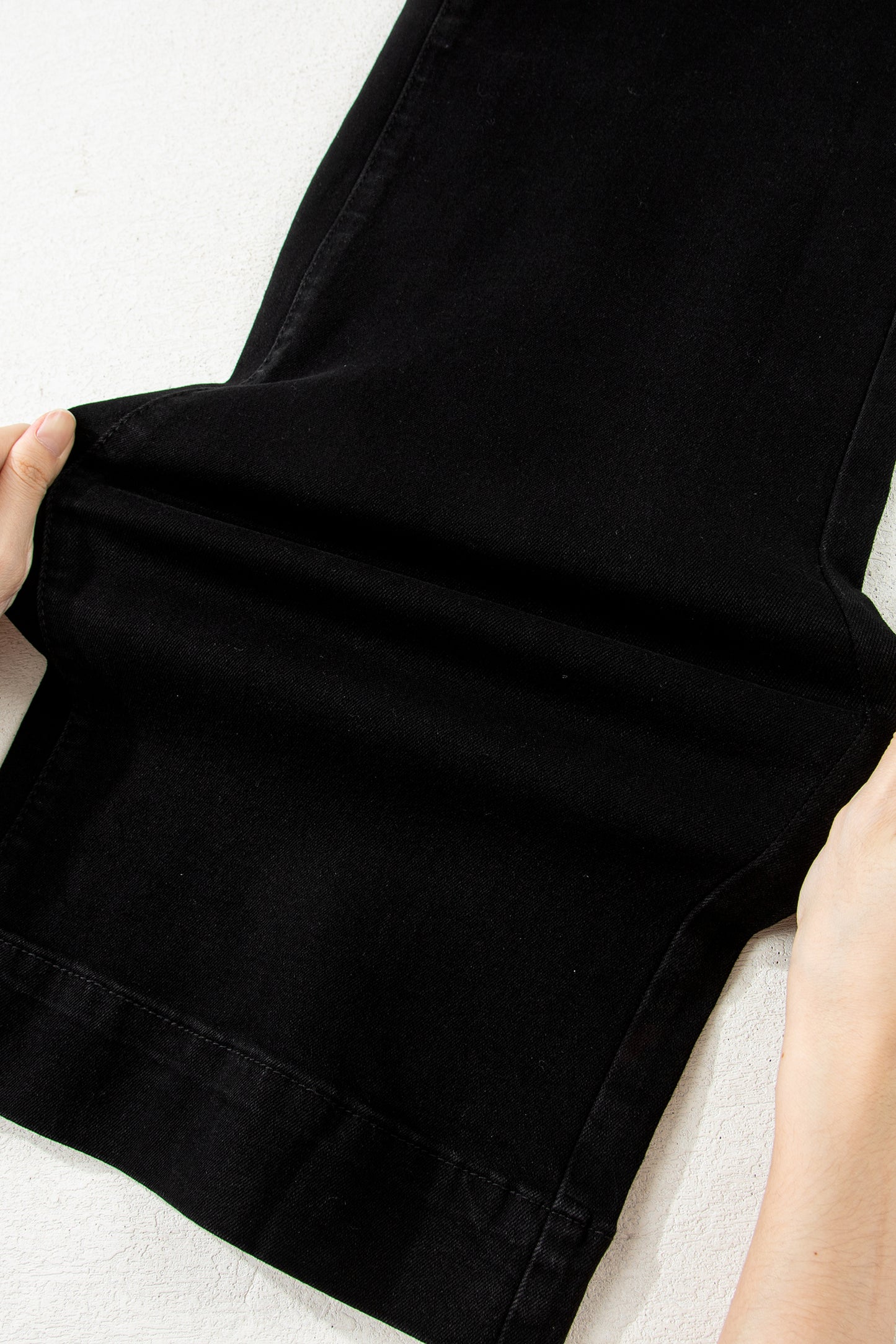 Black high rise wide leg jeans with double-button waistband, front pockets and cropped hem.