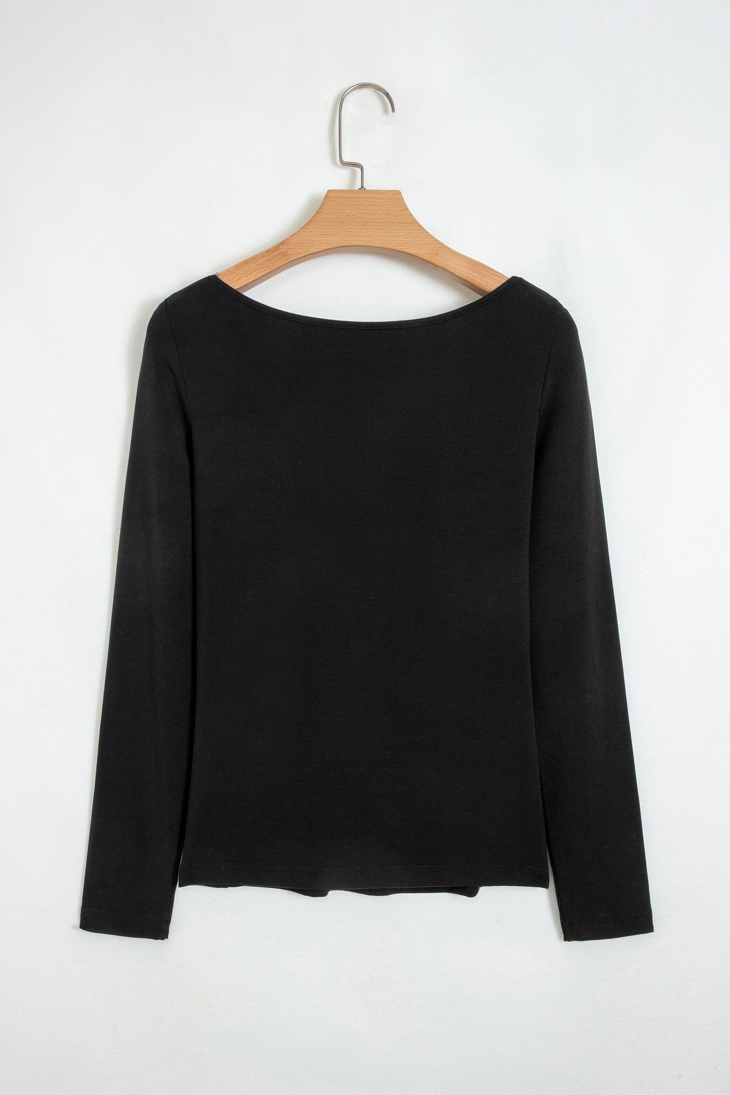 Black fitted long sleeve top with floral lace-trim V-neckline and soft stretch fabric styled with white pants.