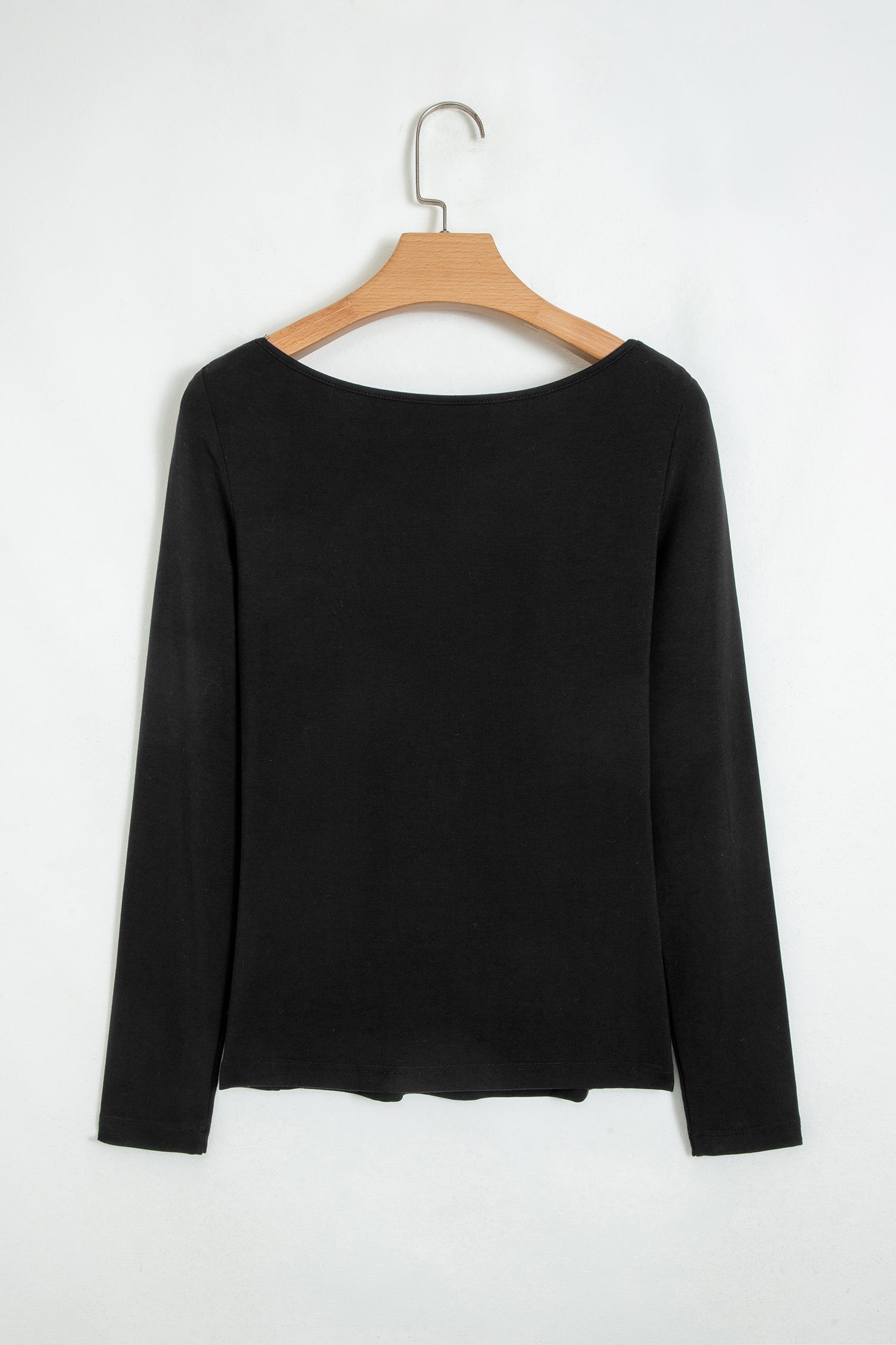 Black fitted long sleeve top with floral lace-trim V-neckline and soft stretch fabric styled with white pants.