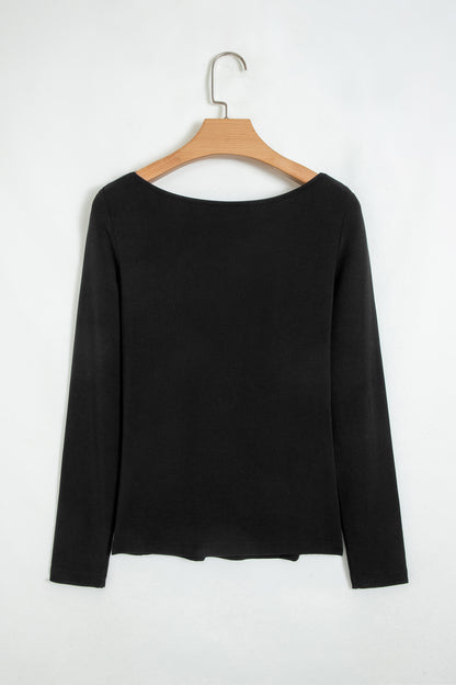 Black fitted long sleeve top with floral lace-trim V-neckline and soft stretch fabric styled with white pants.