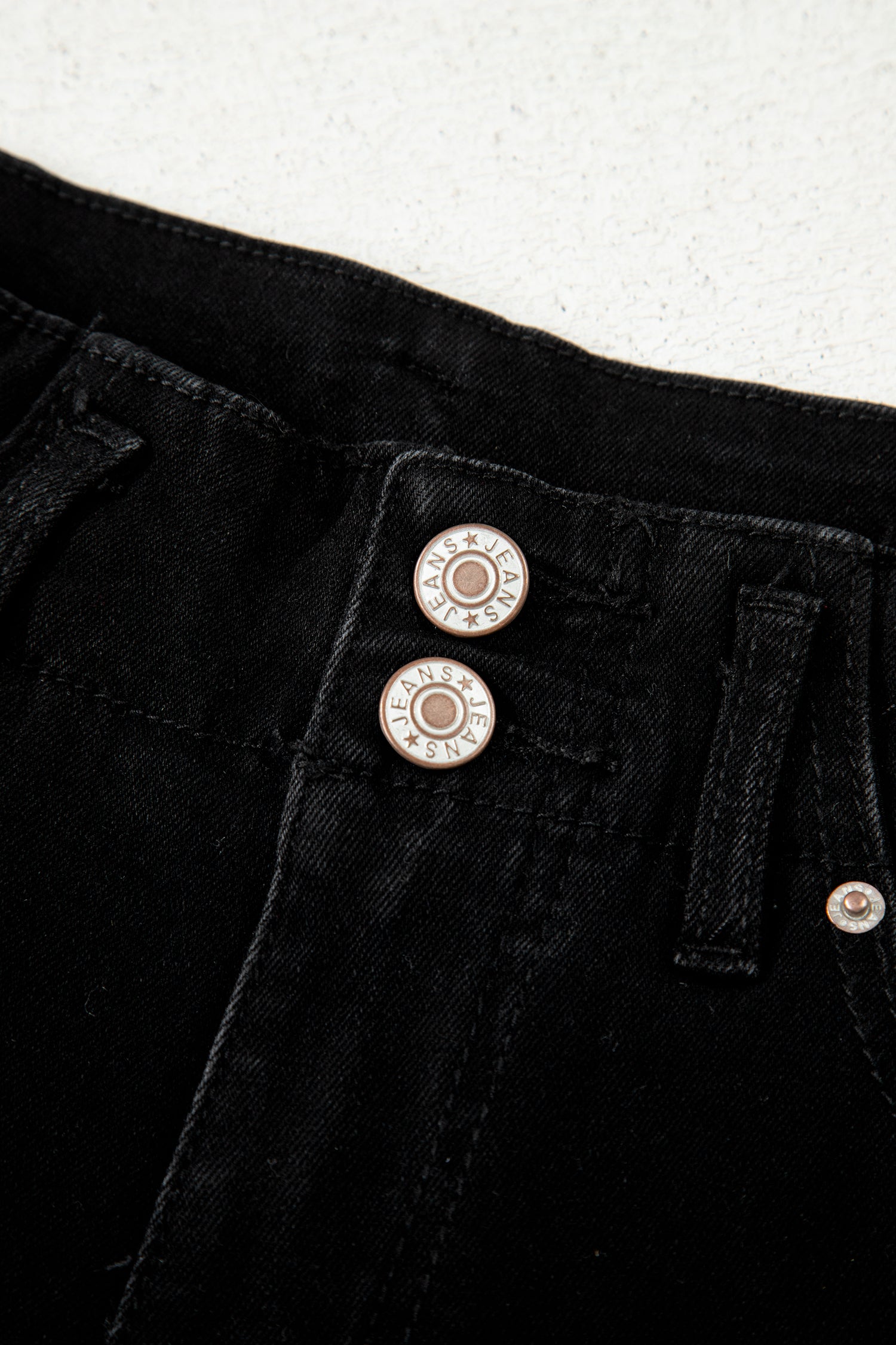Black high rise wide leg jeans with double-button waistband, front pockets and cropped hem.
