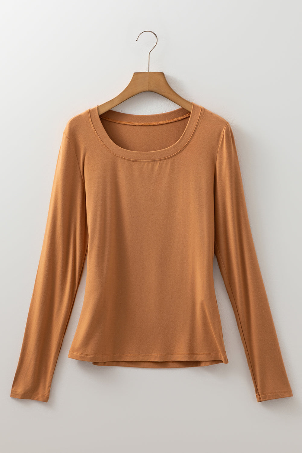 Woman wearing a Caramel Mocha scoop neck long sleeve top with a soft casual fit and white pants.