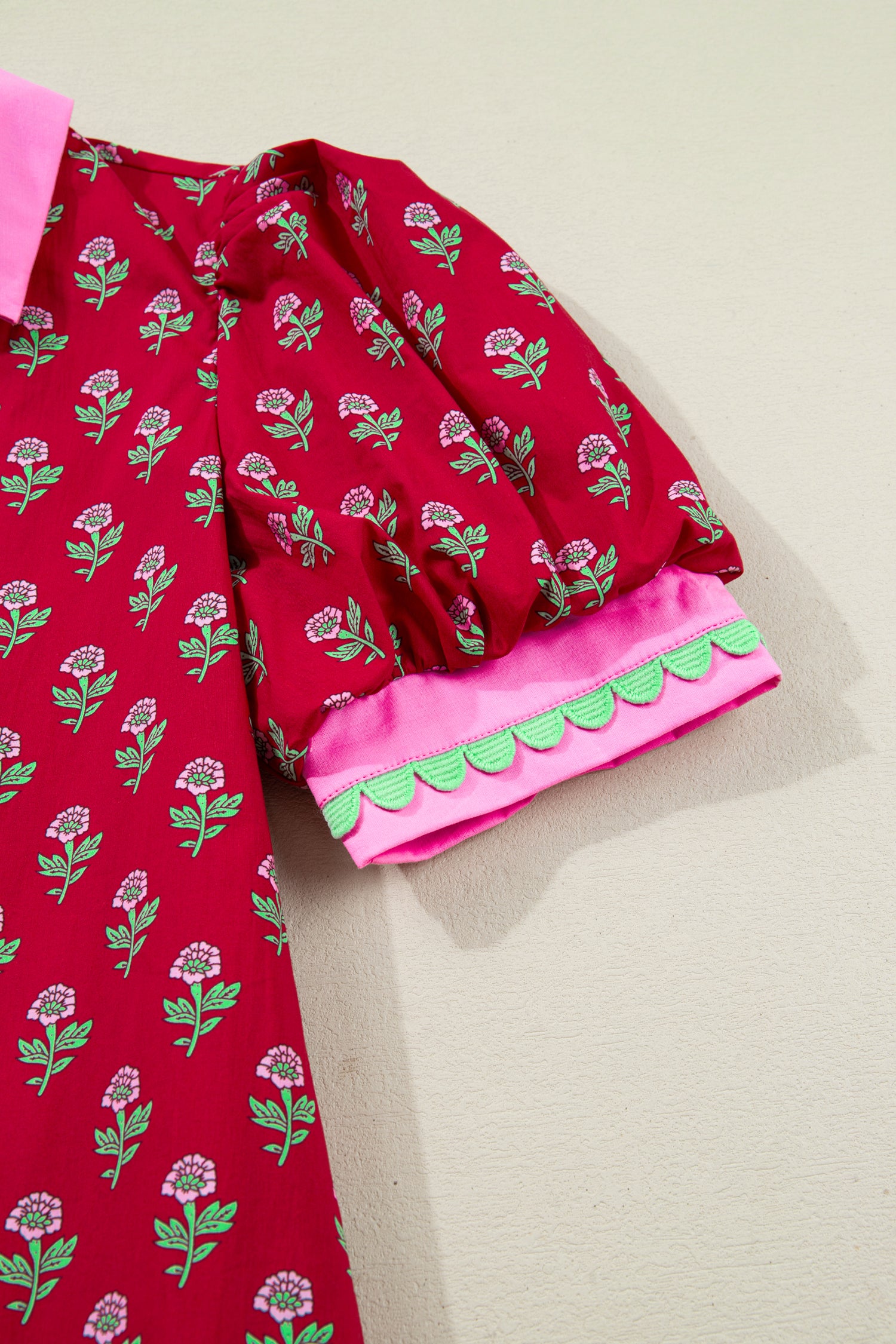 Red floral mini dress with pink collared neckline, mint scalloped trim, short puff sleeves, and a ruffled drop-waist hem