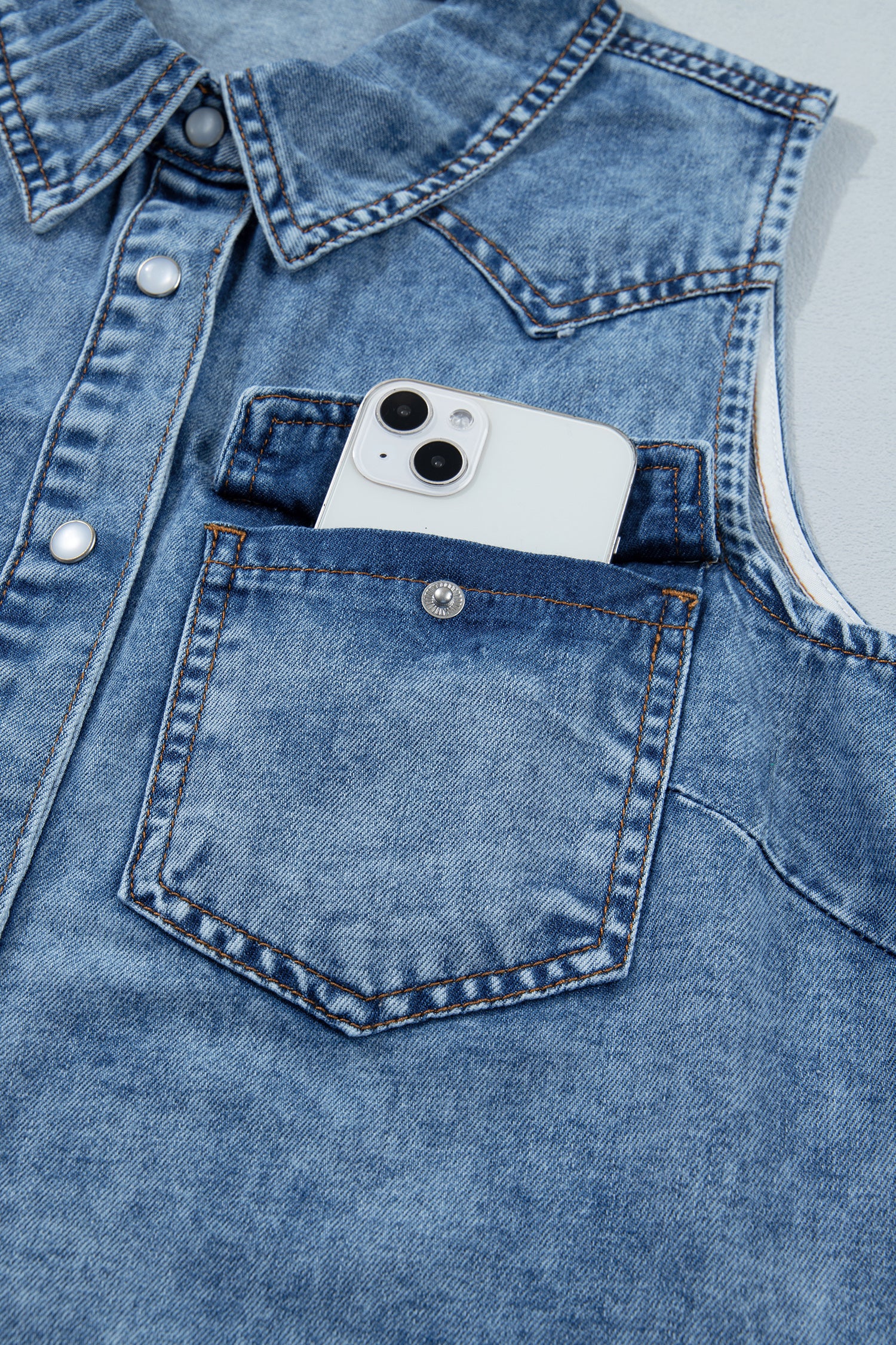 Women's Vintage Denim Wash Acid Wash Sleeveless Denim Button-Up Tank Top featuring a collared neckline, snap button front, western yoke, flap chest pockets, and curved hem.