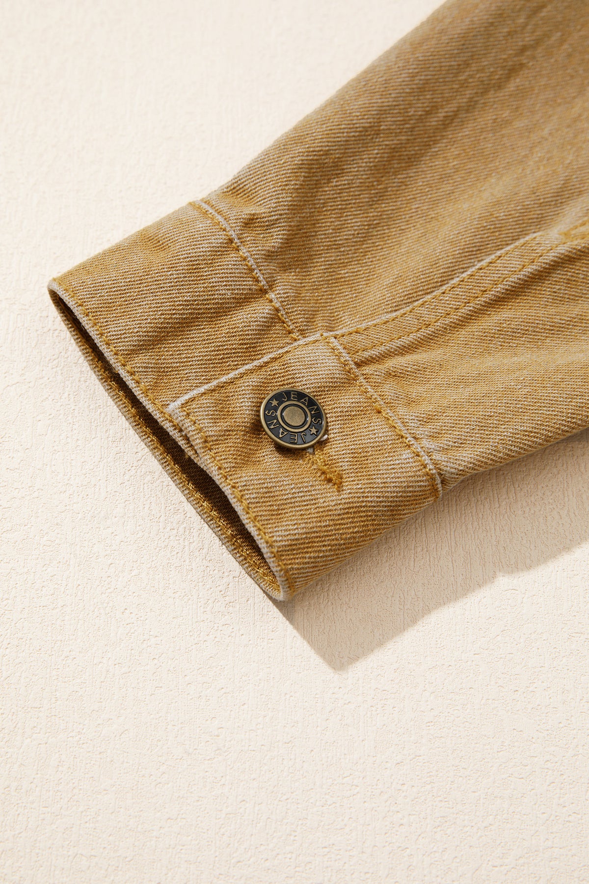 Tan women's denim jacket with metal button front, collared neckline, long sleeves, patch pockets, and relaxed fit.