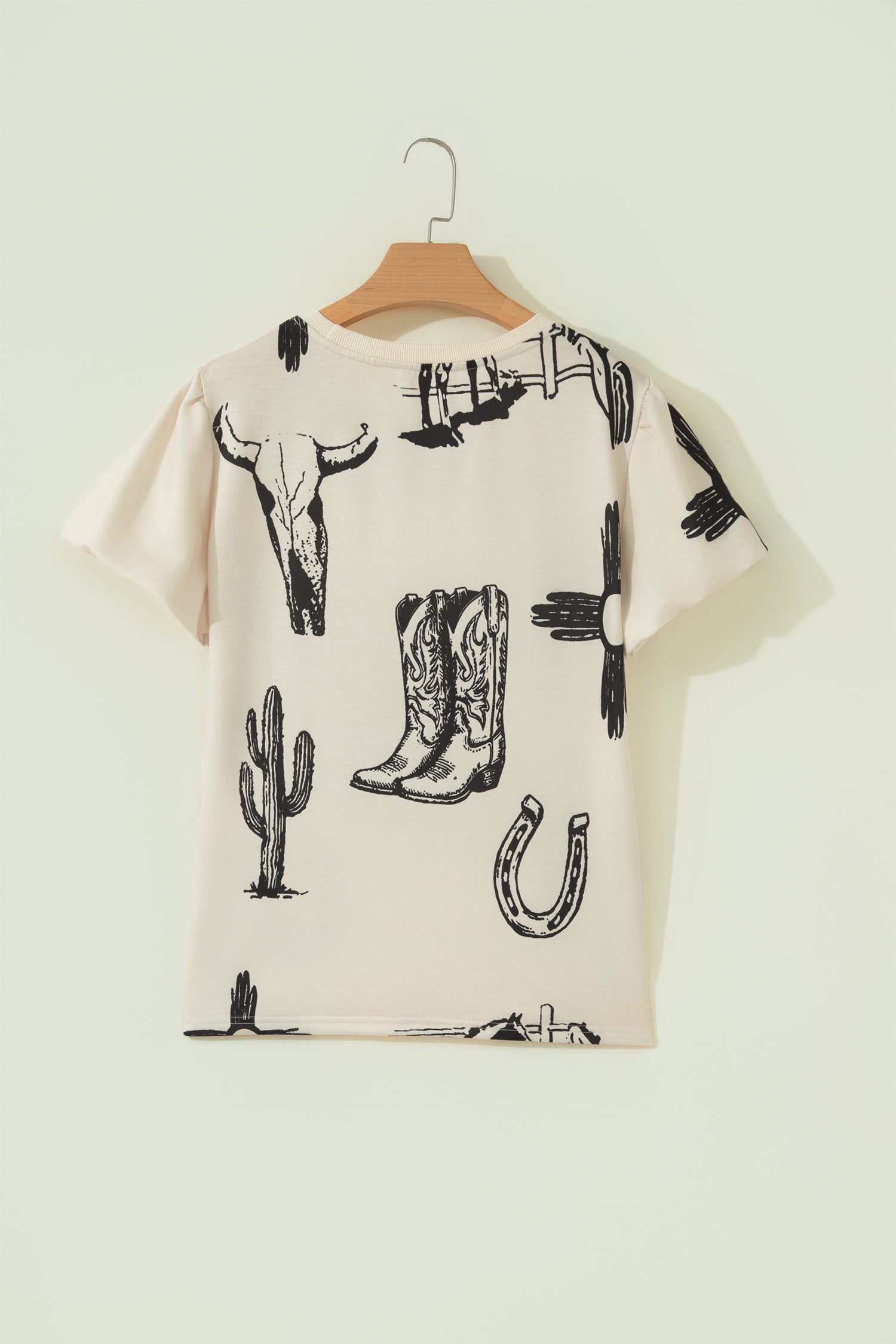 Cream Western graphic print top with crew neckline, short sleeves with gathered armholes, and black cowboy boot, cactus, horseshoe, and Southwestern motifs.