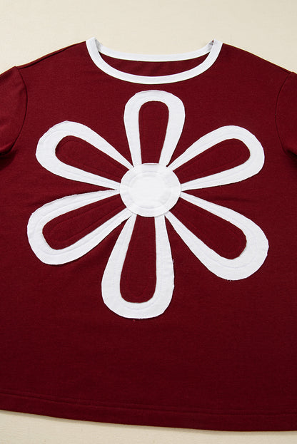 Red Dahlia women’s long sleeve top with round white contrast neckline, white sleeve bands, oversized daisy patch front, and relaxed shift silhouette.