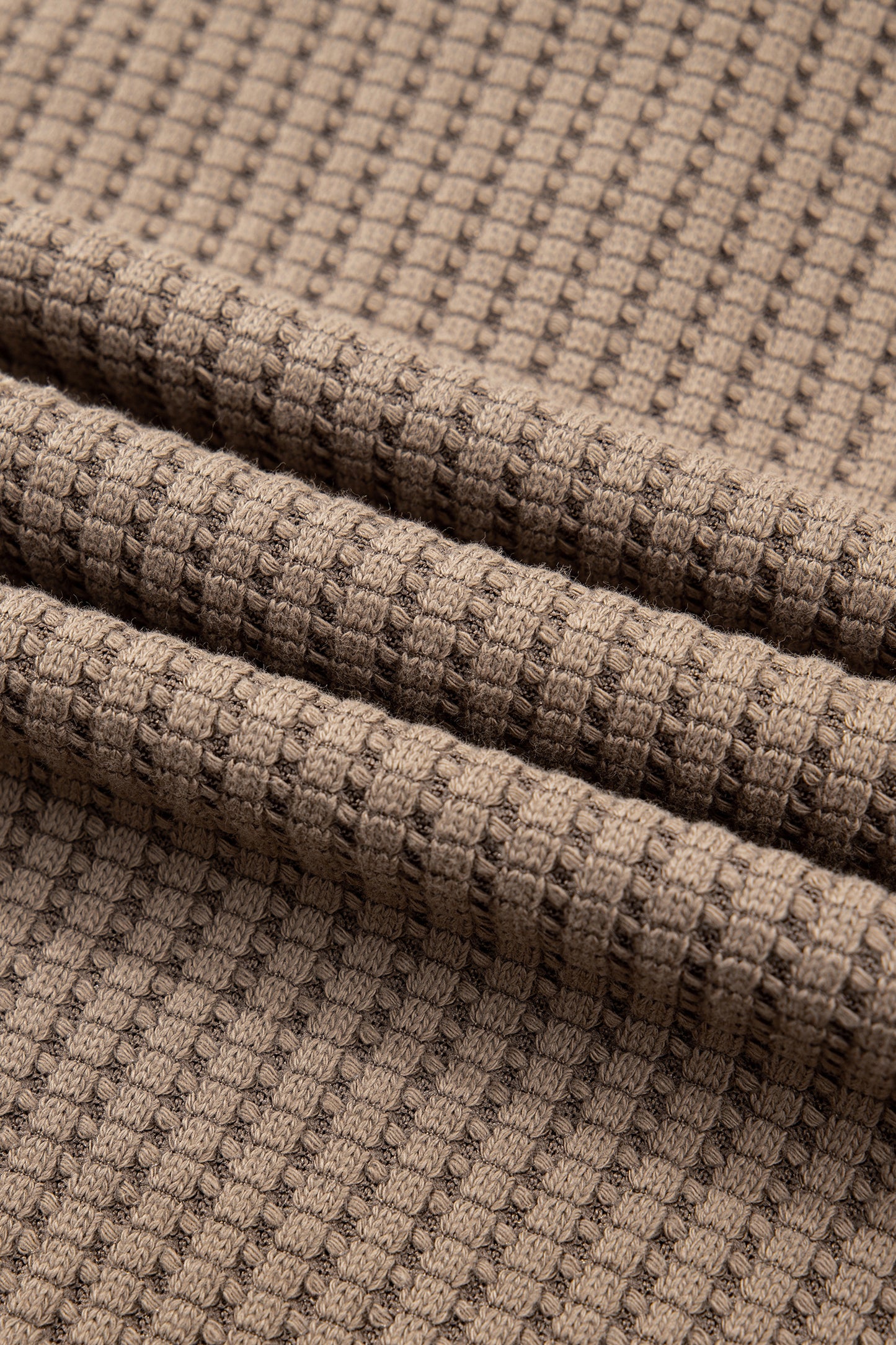 Woman wearing a Mocha textured waffle knit pullover with snap collar, relaxed long sleeves, and ribbed cuffs with white pants.
