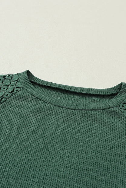 Forest green waffle knit long sleeve top with floral lace shoulder panels, crew neckline, relaxed fit, and balloon sleeves.