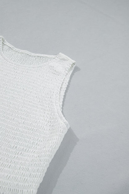 Women's white smocked sleeveless peplum top with embroidered eyelet hem, round neckline, textured bodice, and feminine boutique style.