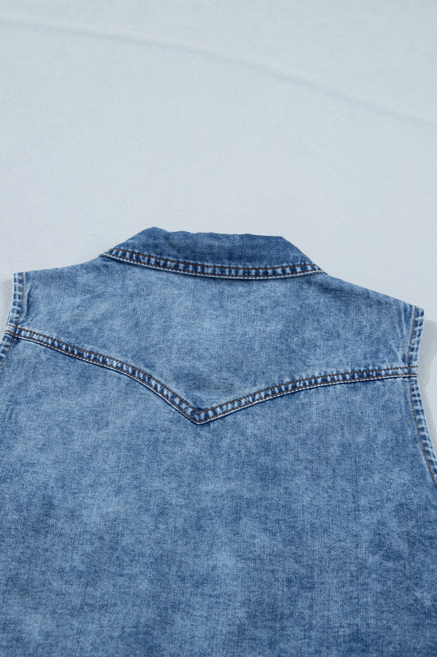 Women's Vintage Denim Wash Acid Wash Sleeveless Denim Button-Up Tank Top featuring a collared neckline, snap button front, western yoke, flap chest pockets, and curved hem.