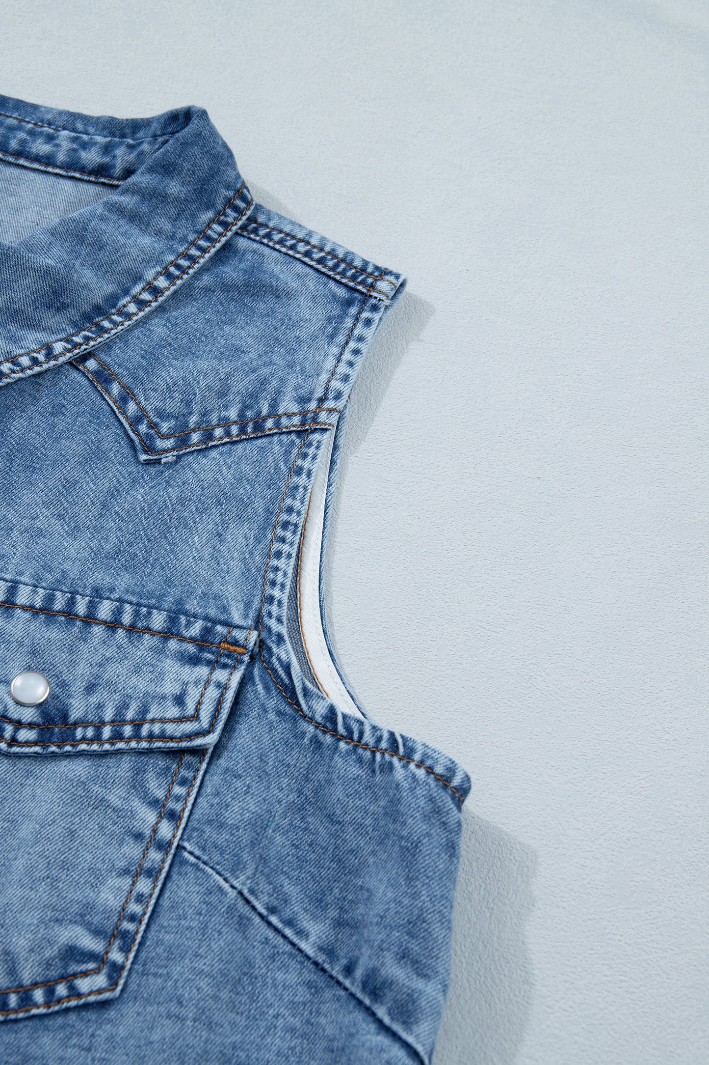 Women's Vintage Denim Wash Acid Wash Sleeveless Denim Button-Up Tank Top featuring a collared neckline, snap button front, western yoke, flap chest pockets, and curved hem.