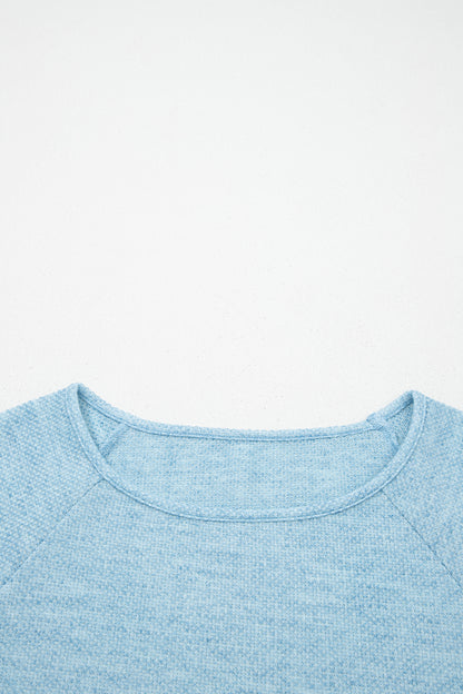 Powder Blue textured raglan long sleeve top with round neckline, relaxed fit, and curved hem