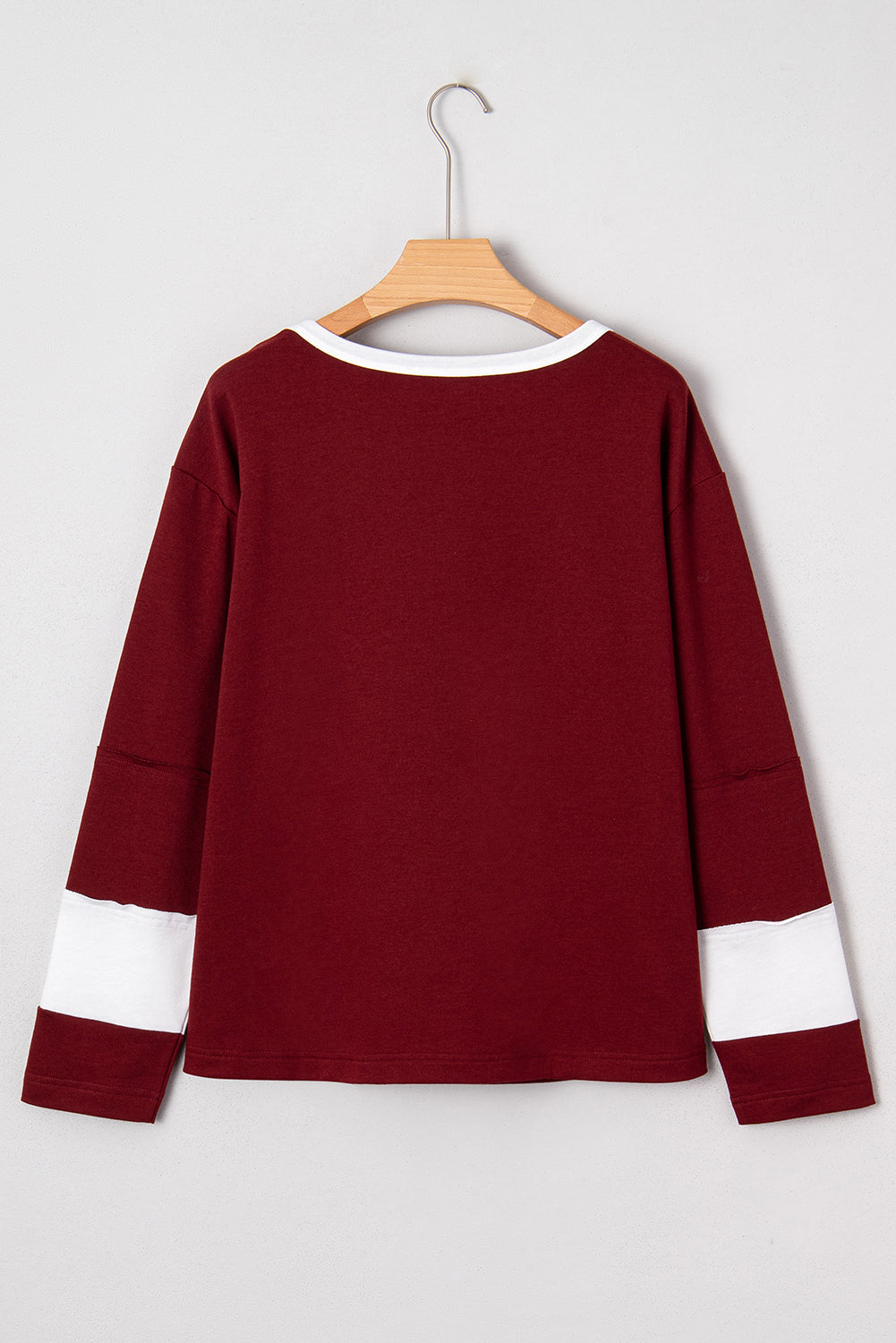 Red Dahlia women’s long sleeve top with round white contrast neckline, white sleeve bands, oversized daisy patch front, and relaxed shift silhouette.