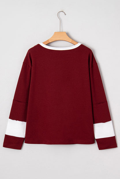 Red Dahlia women’s long sleeve top with round white contrast neckline, white sleeve bands, oversized daisy patch front, and relaxed shift silhouette.