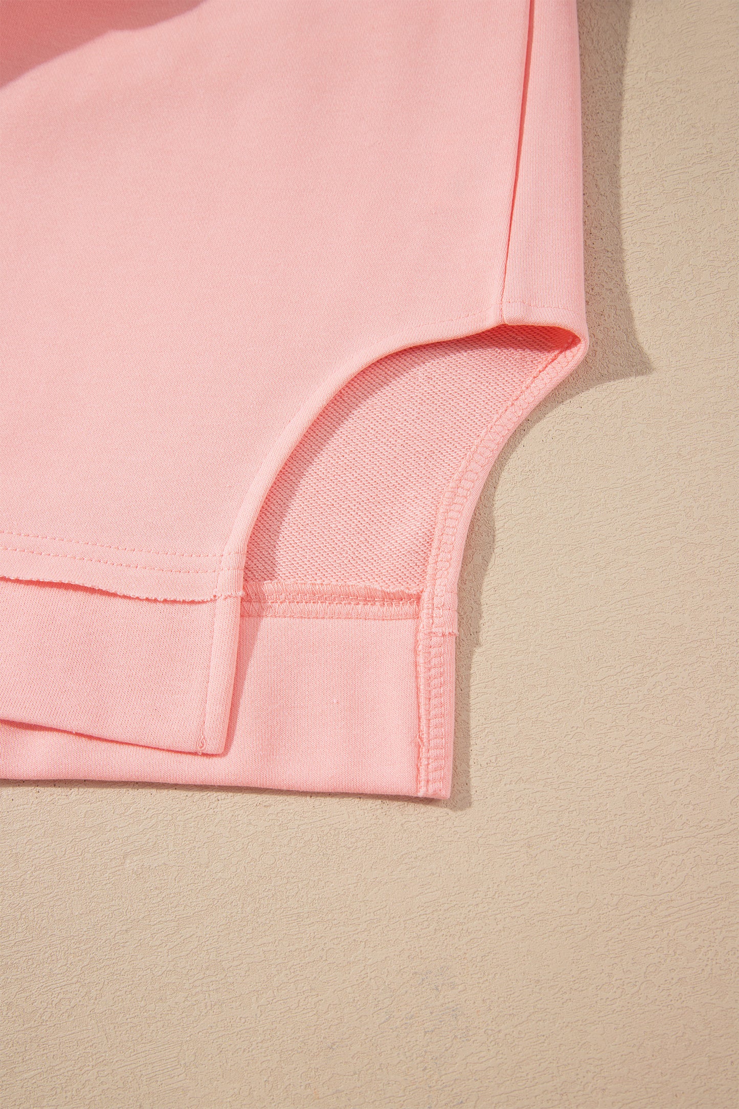 Pink crew neck long sleeve top with asymmetrical paneled body design and blue striped color block sleeves with contrasting orange accents.