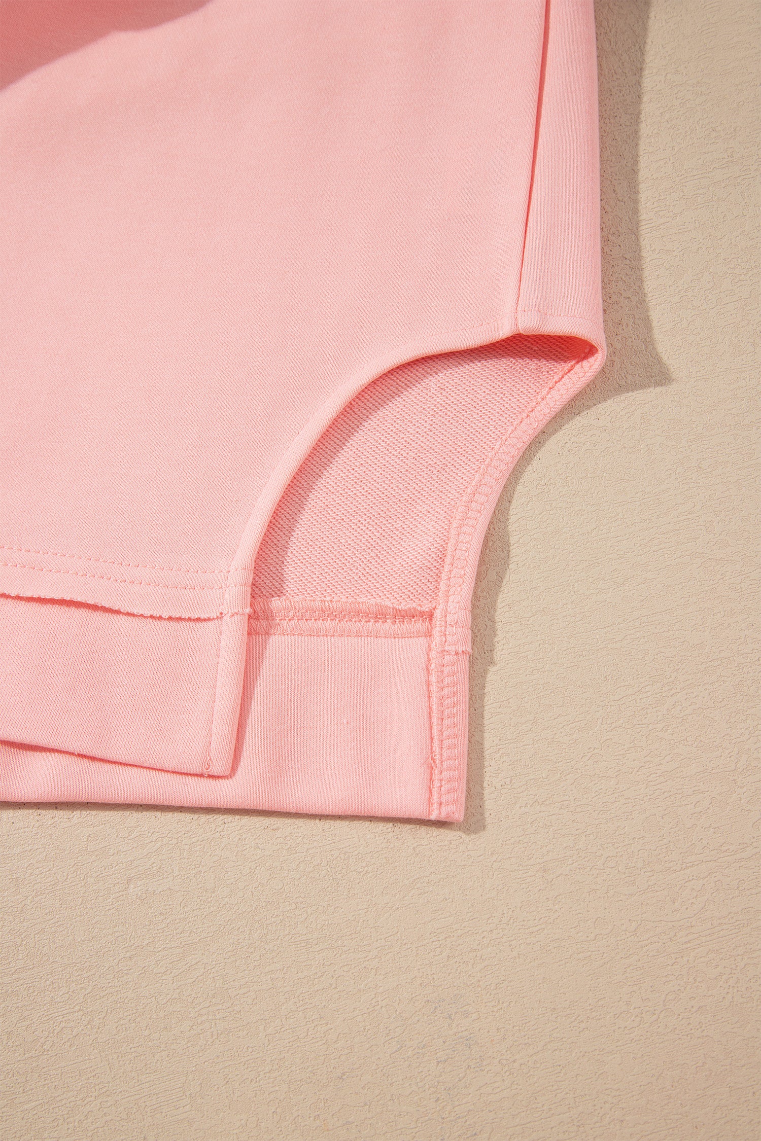 Pink crew neck long sleeve top with asymmetrical paneled body design and blue striped color block sleeves with contrasting orange accents.