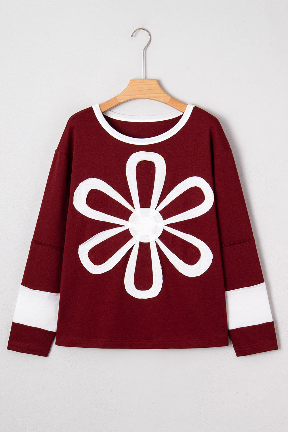 Red Dahlia women’s long sleeve top with round white contrast neckline, white sleeve bands, oversized daisy patch front, and relaxed shift silhouette.
