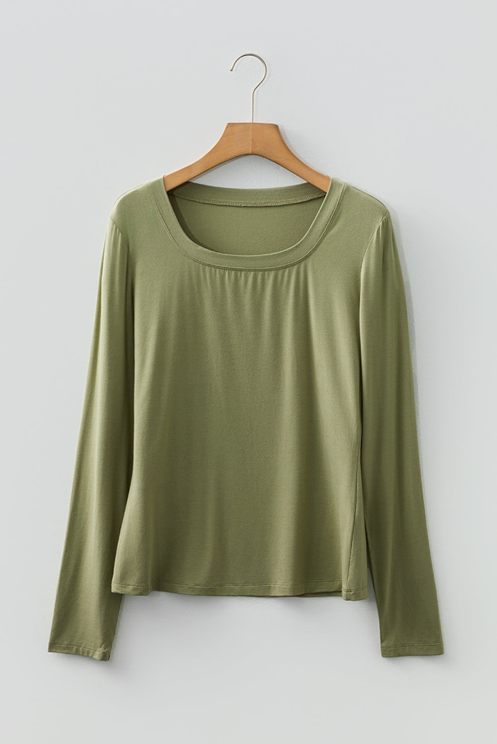 Woman wearing a Soft Sage scoop neck long sleeve top with a soft casual fit and white pants.