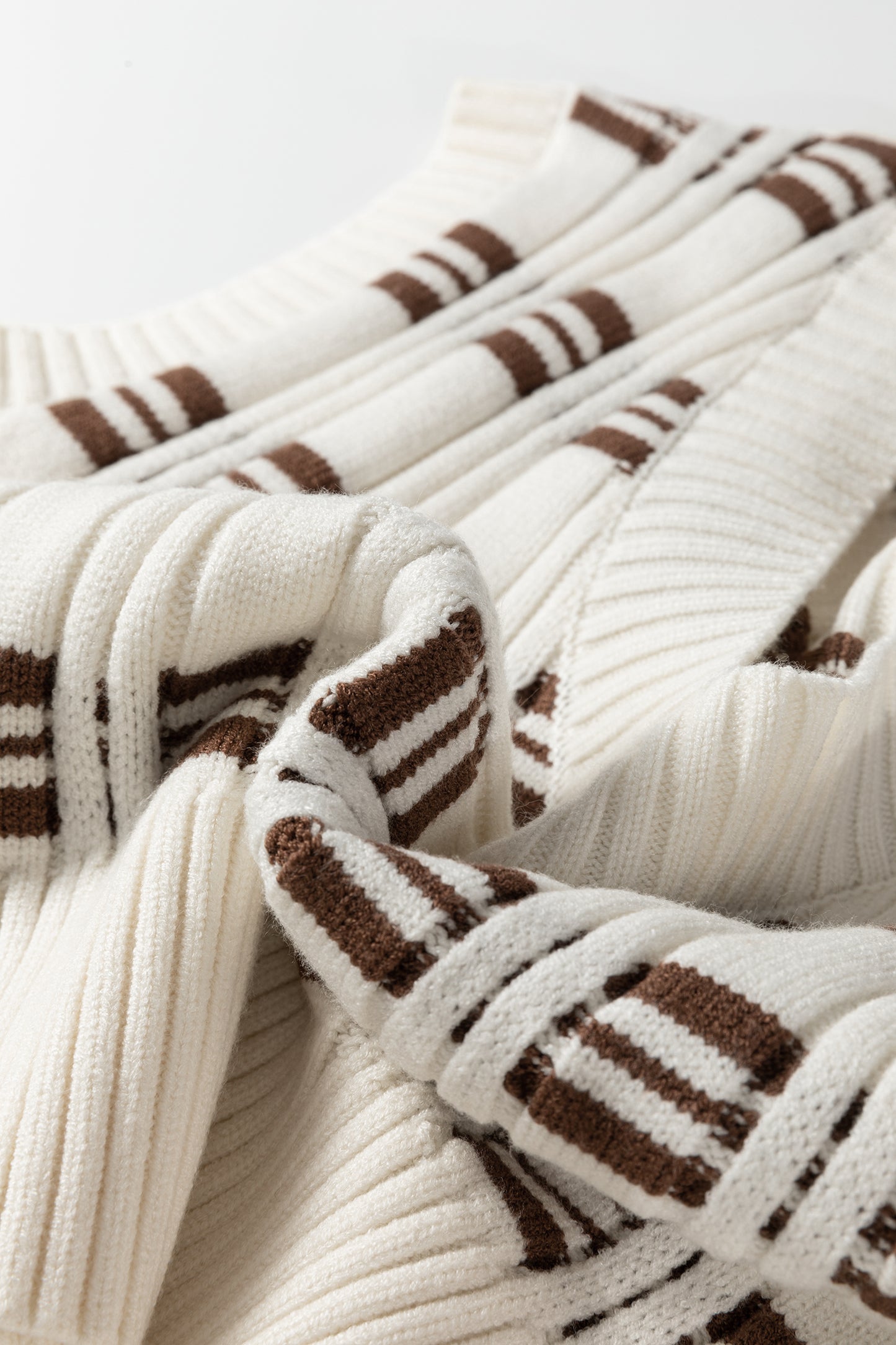 Oatmeal knit sweater vest with brown striped pattern, V-neckline, sleeveless design, and ribbed trim.
