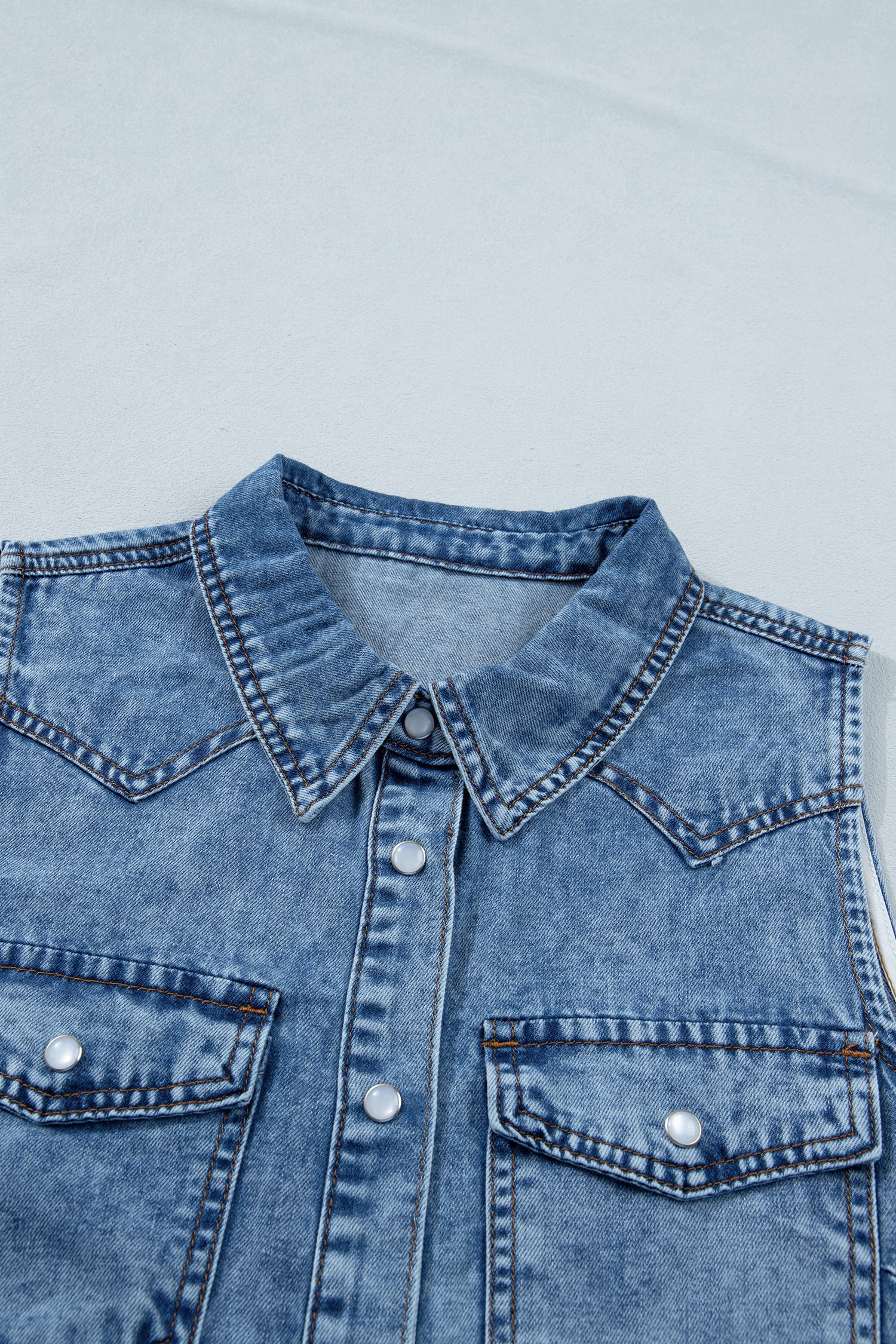 Women's Vintage Denim Wash Acid Wash Sleeveless Denim Button-Up Tank Top featuring a collared neckline, snap button front, western yoke, flap chest pockets, and curved hem.