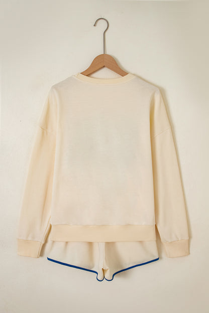 Cream Game Day embroidered sweatshirt and matching drawstring shorts set featuring long sleeves, blue contrast trim, relaxed fit, and casual sporty style.