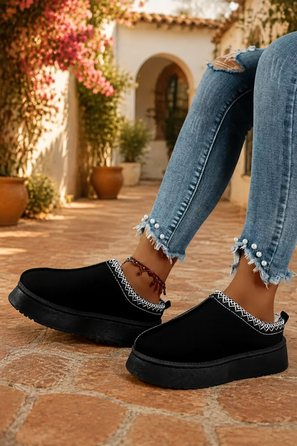 Black faux-suede platform slippers with cream plush lining, round toes, and contrasting white stitched collar trim