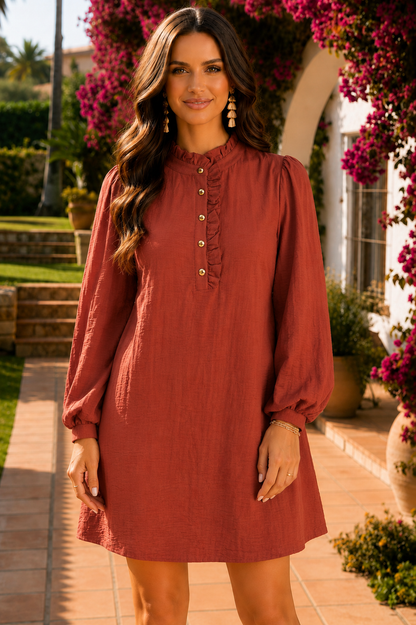 Rust long sleeve shift mini dress with a ruffle mock neckline, decorative button-front placket, balloon sleeves with cuffed wrists, and a relaxed silhouette.