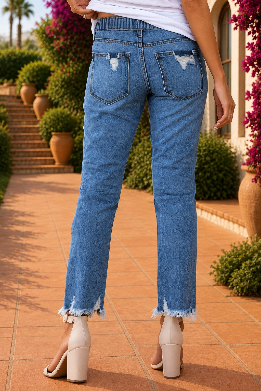 Medium wash blue distressed slim straight leg jeans with drawstring elastic waist and raw hem