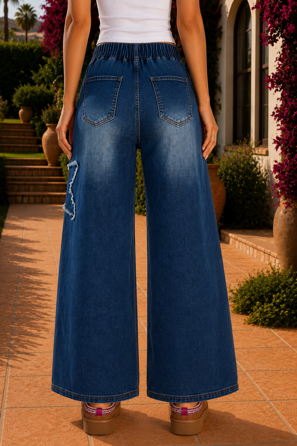 Women's medium wash denim high-waist wide-leg jeans with oversized frayed star patch appliqués, full-length relaxed fit, button fly, and functional pockets.