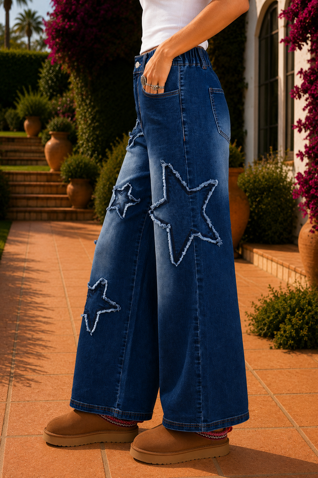 Women's medium wash denim high-waist wide-leg jeans with oversized frayed star patch appliqués, full-length relaxed fit, button fly, and functional pockets.
